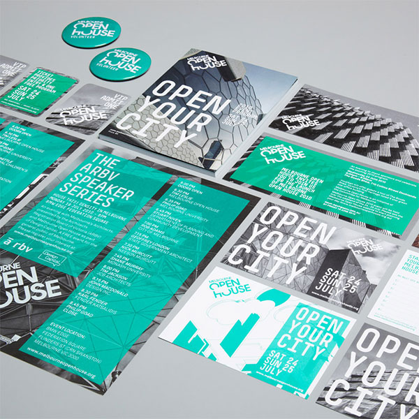 Assorted promotional materials laid out on a flat surface, including brochures, flyers, posters, and stickers. The design highlights modern architecture images with a teal, black, and white color scheme. The visual presence is striking with prominent text reading "Open Your City" and "Open House.